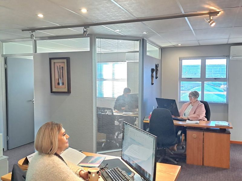 Professional office space featuring glass partitions, suspended ceilings with integrated lighting, and an air conditioning unit.