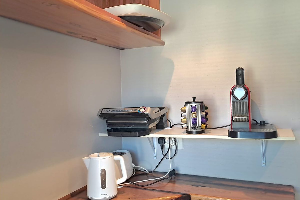 A compact kitchenette area featuring custom wooden countertops and additional wall-mounted shelving for storage.