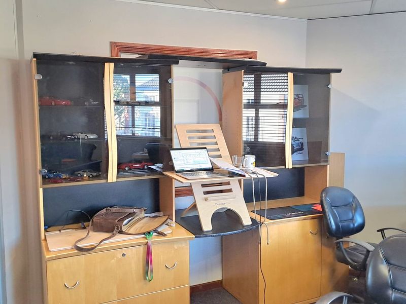A functional office space featuring built-in cabinetry, recessed ceiling lighting, and suspended ceiling tiles, providing a practical work environment.