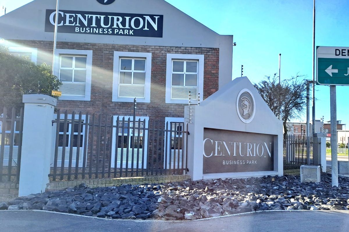 Front exterior view of Centurion Business Park featuring brick facade, secure perimeter fencing, and professional signage.