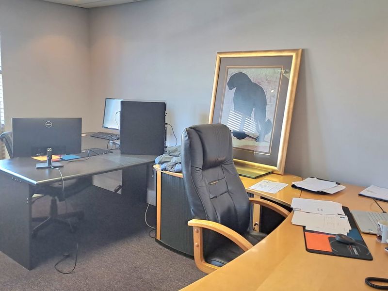A functional office space featuring a suspended ceiling with recessed lighting and carpeted flooring, suitable for a professional work environment.