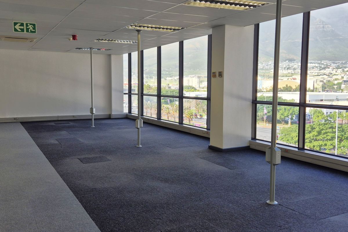 Spacious, vacant open-plan office area featuring large floor-to-ceiling windows with mountain views, suspended ceilings, and carpeted flooring.