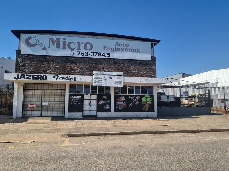 Front elevation of a commercial retail property featuring brick facade, security gates, and prominent business signage.