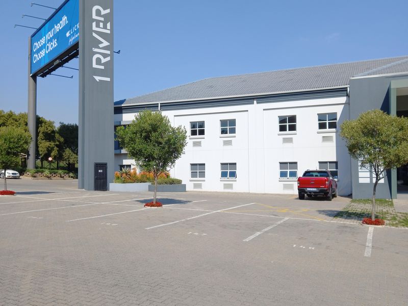Exterior view of a commercial office building featuring a paved parking lot and prominent branded signage pylon.