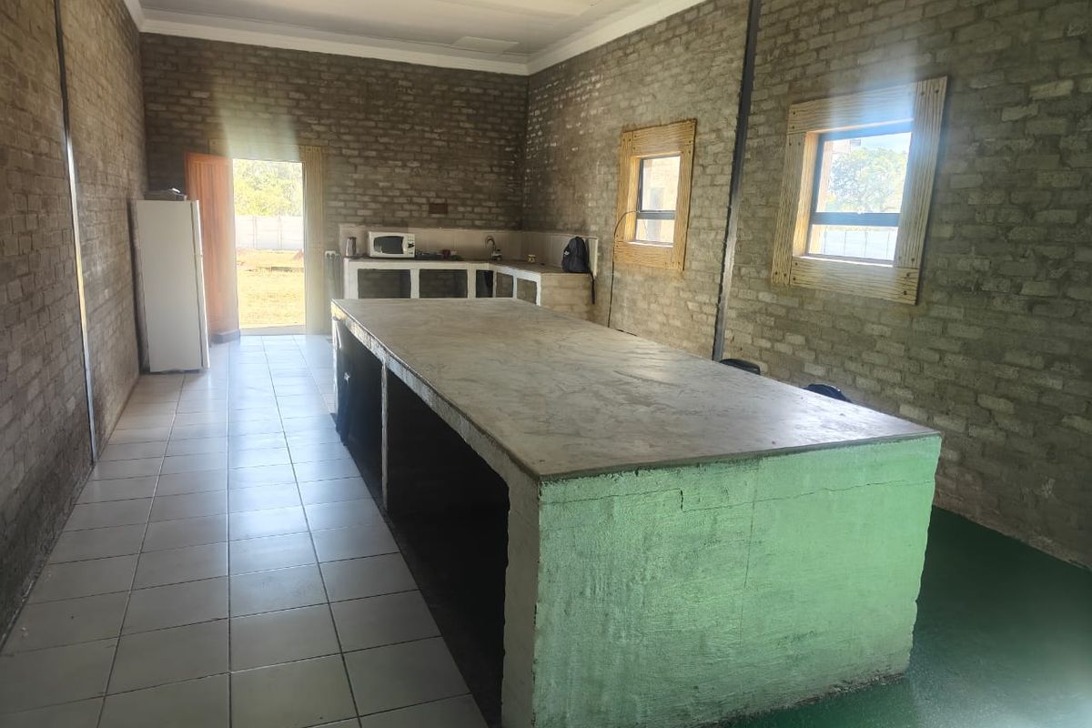A spacious, industrial-style kitchen featuring exposed brick walls, a large built-in concrete island, and direct access to the exterior.