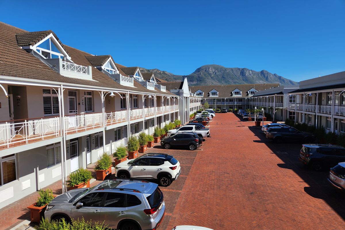 An elevated view of a well-maintained office complex featuring a central brick-paved courtyard and mountain views.