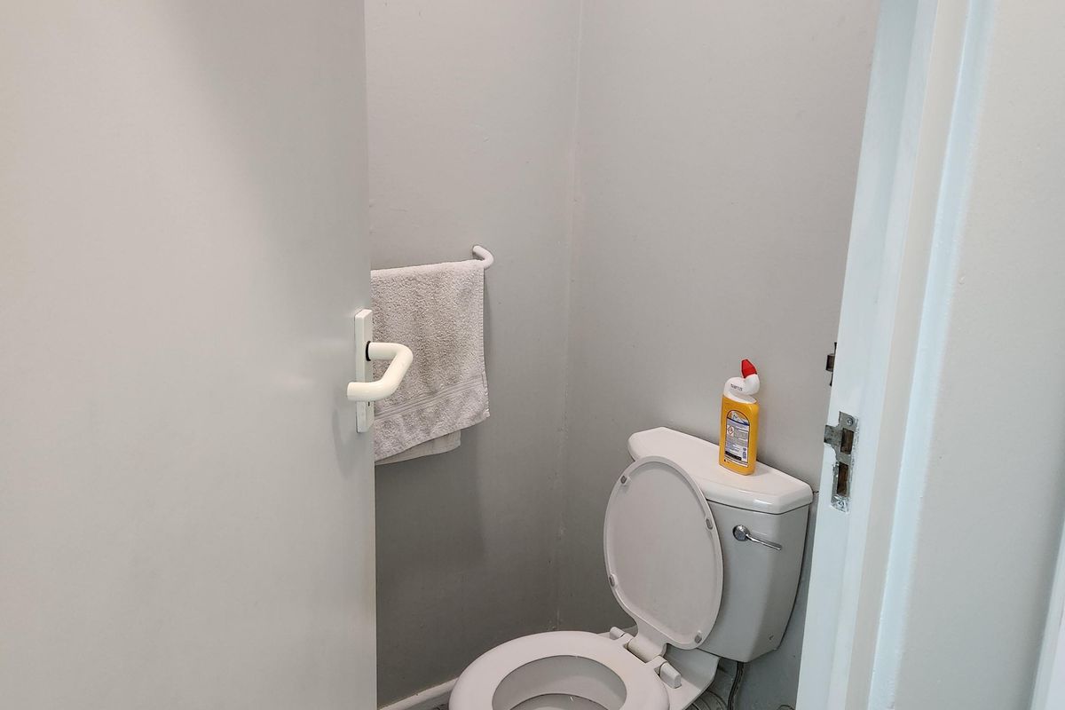 A compact office restroom featuring a standard toilet, tiled flooring, and a wall-mounted towel rail.