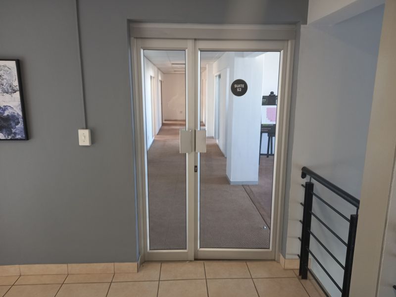 Entrance to office suite S2 featuring aluminium framed glass double doors, tiled entryway, and carpeted interior hallway.