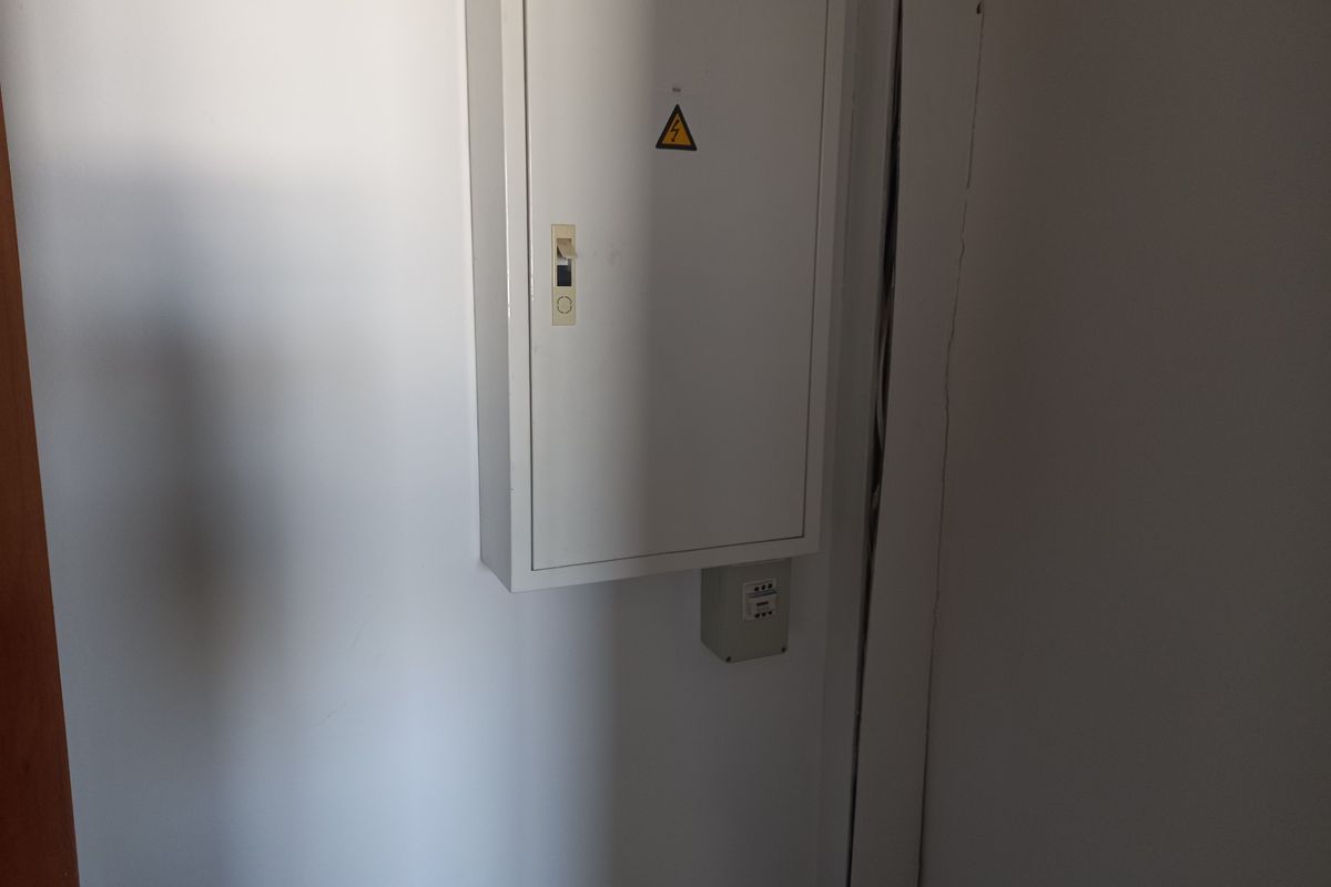 A utility area featuring a wall-mounted electrical distribution board and associated junction box.