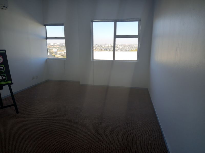 A vacant office space featuring carpeted flooring, air conditioning, and large windows providing natural light and city views.