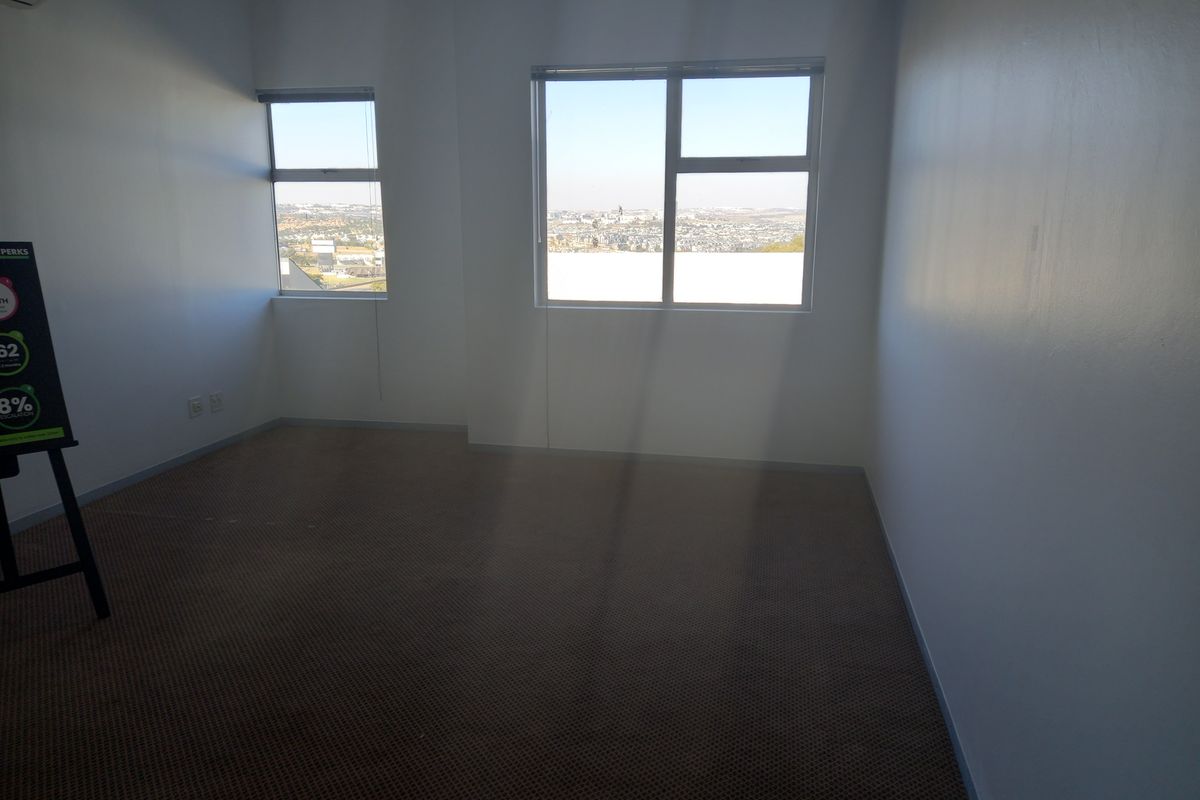A vacant office space featuring carpeted flooring, air conditioning, and large windows providing natural light and city views.