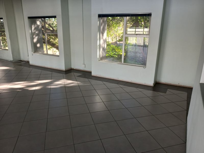 A bright, vacant office space featuring large windows, tiled flooring, and neutral walls, ready for professional fit-out.