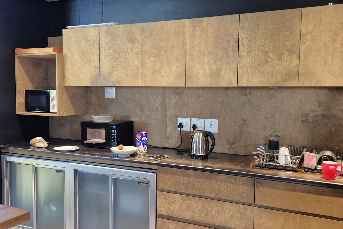 Office kitchenette featuring wood-grain cabinetry, integrated under-counter refrigeration, and a dark countertop, providing a functional break area for staff.
