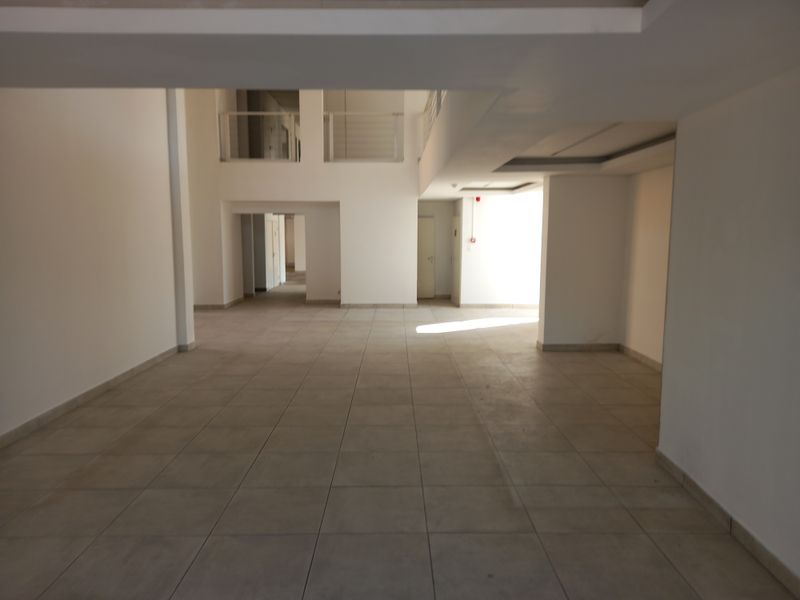 Spacious, open-plan office area featuring tiled flooring, a mezzanine level with railing, and a clean, modern layout suitable for various business configurations.