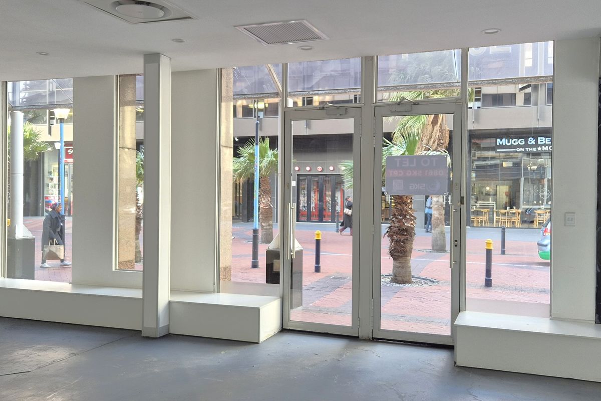 Empty retail storefront featuring large glass windows, double entry doors, and built-in display plinths, offering excellent visibility in a busy pedestrian area.
