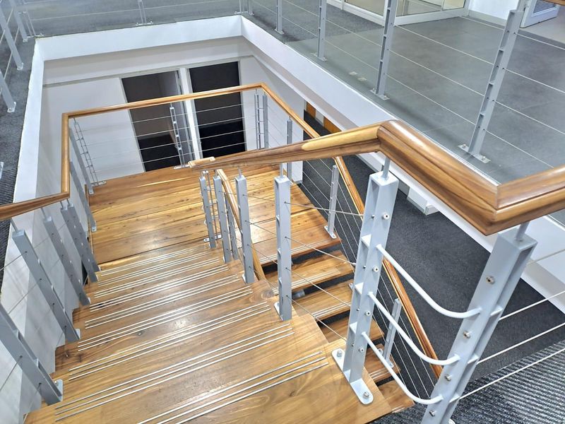 A modern office staircase featuring timber treads with anti-slip nosing, complemented by a sleek metal balustrade and polished timber handrail.