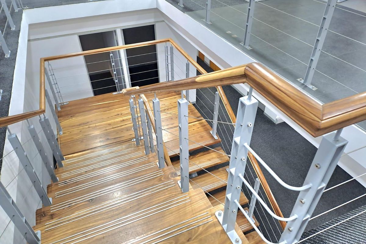 A modern office staircase featuring timber treads with anti-slip nosing, complemented by a sleek metal balustrade and polished timber handrail.