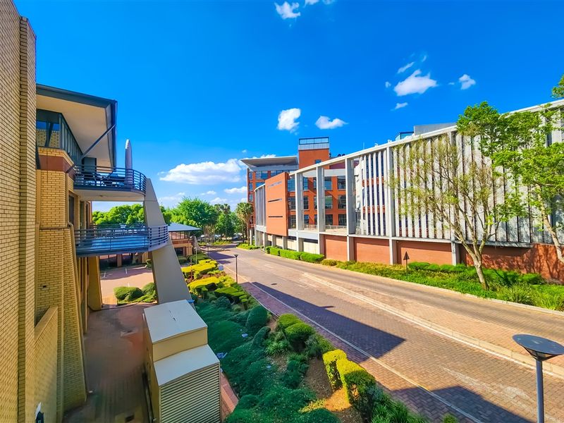 An elevated view of the office complex exterior, featuring brick architecture, multiple balconies, and well-maintained landscaped grounds with paved access roads.