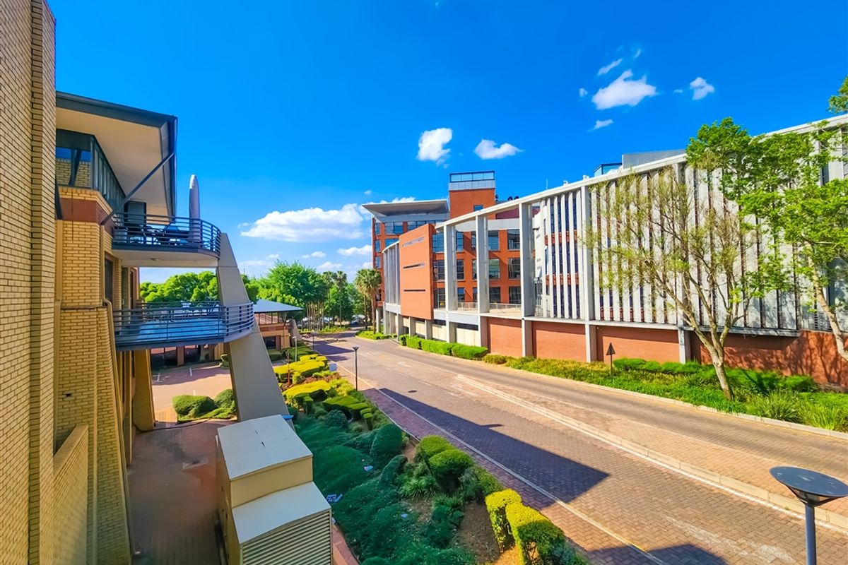 An elevated view of the office complex exterior, featuring brick architecture, multiple balconies, and well-maintained landscaped grounds with paved access roads.