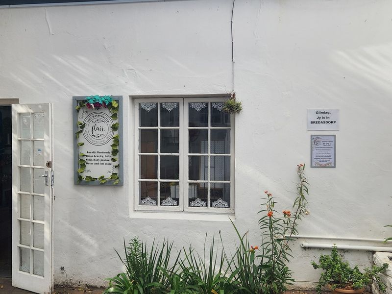 A charming commercial exterior facade featuring white plastered walls, a multi-pane window, and classic french door entrance.