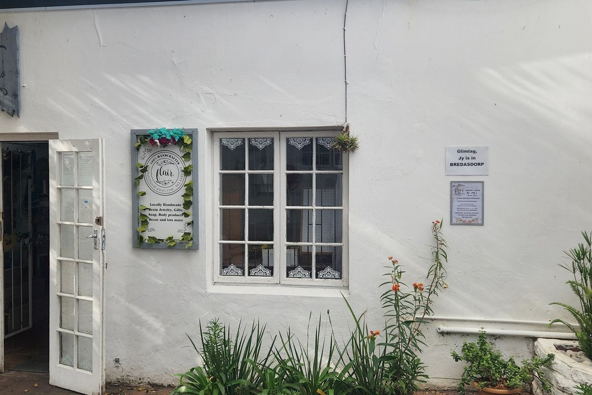 A charming commercial exterior facade featuring white plastered walls, a multi-pane window, and classic french door entrance.