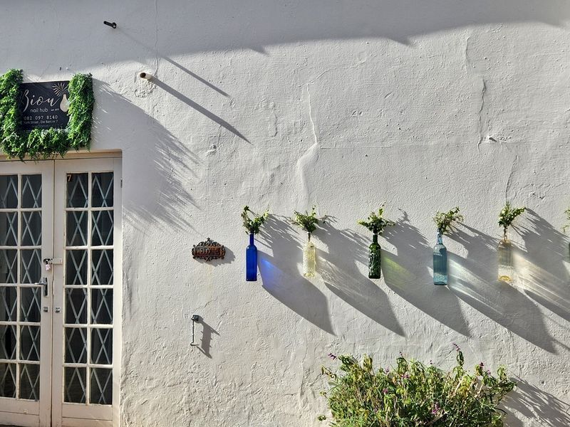 Commercial building entrance featuring a white facade with a classic french door and decorative wall-mounted signage.