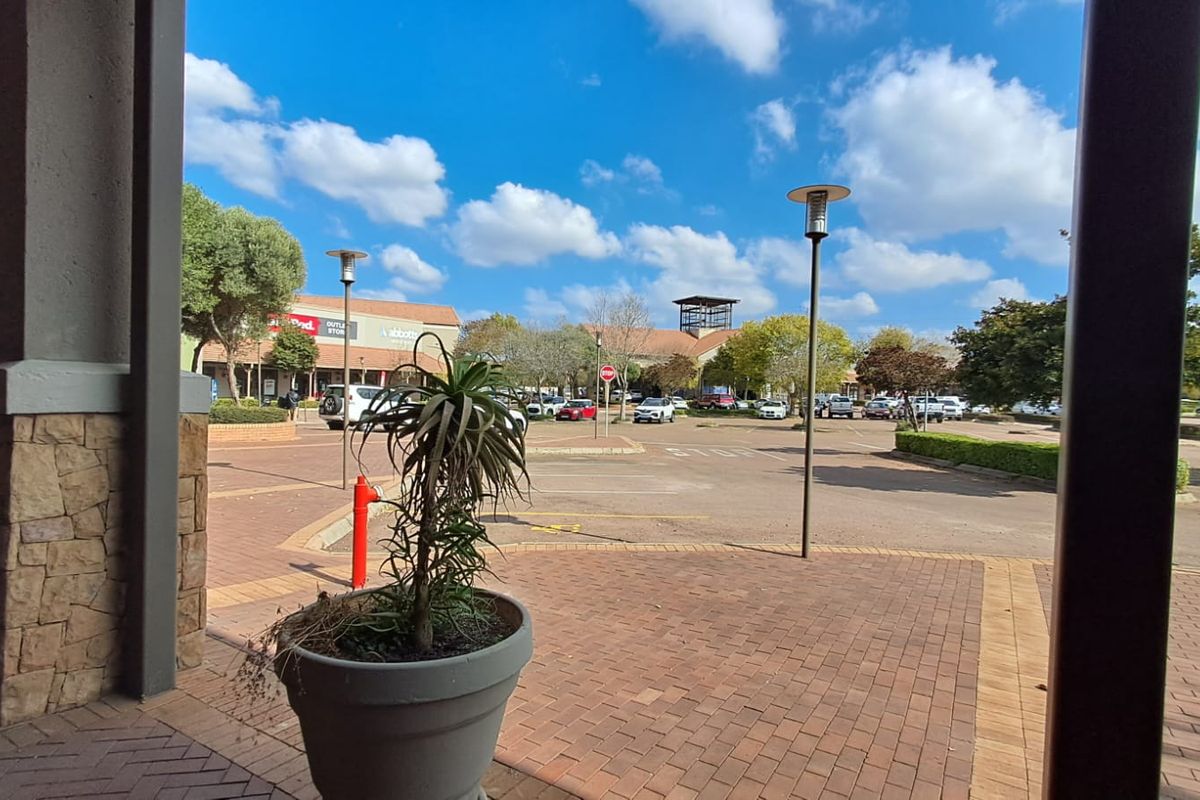 View of the retail center parking area and surrounding commercial buildings from a covered walkway.