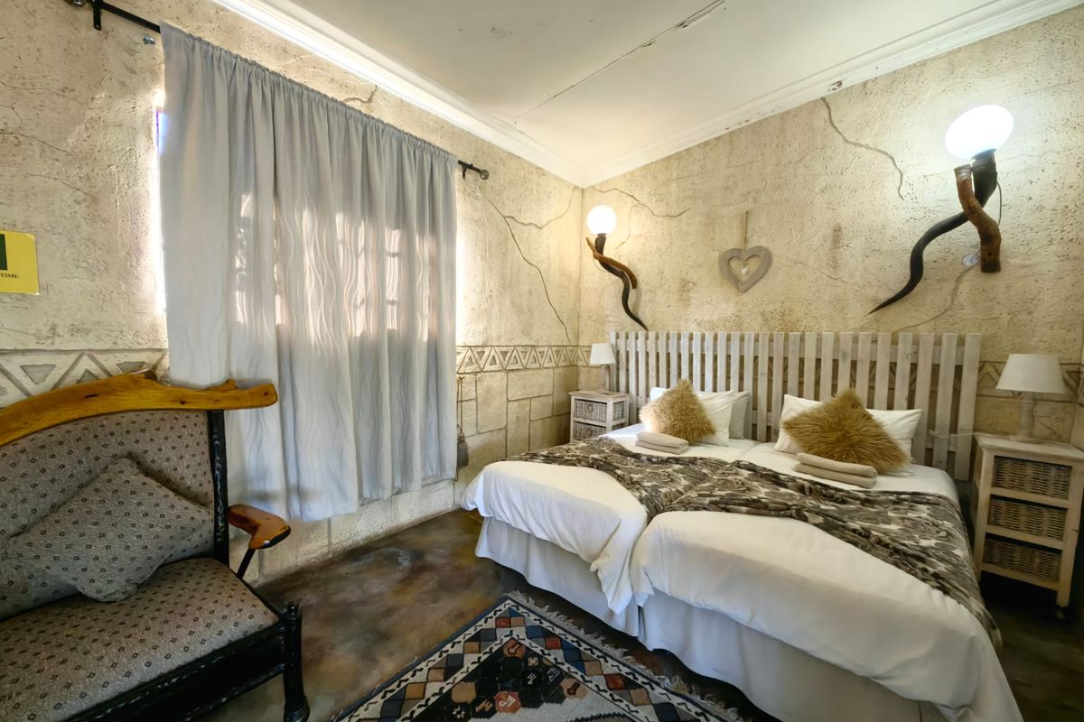 A rustic-style bedroom featuring textured stone-effect walls, a built-in headboard, and a coved ceiling, offering a unique farm-style aesthetic.