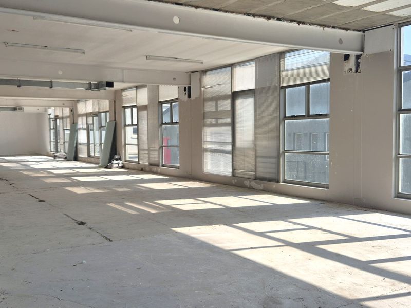 Spacious open-plan office area featuring large windows, exposed industrial-style ceiling ducting, and unfinished concrete flooring, offering a blank canvas for custom fit-out.