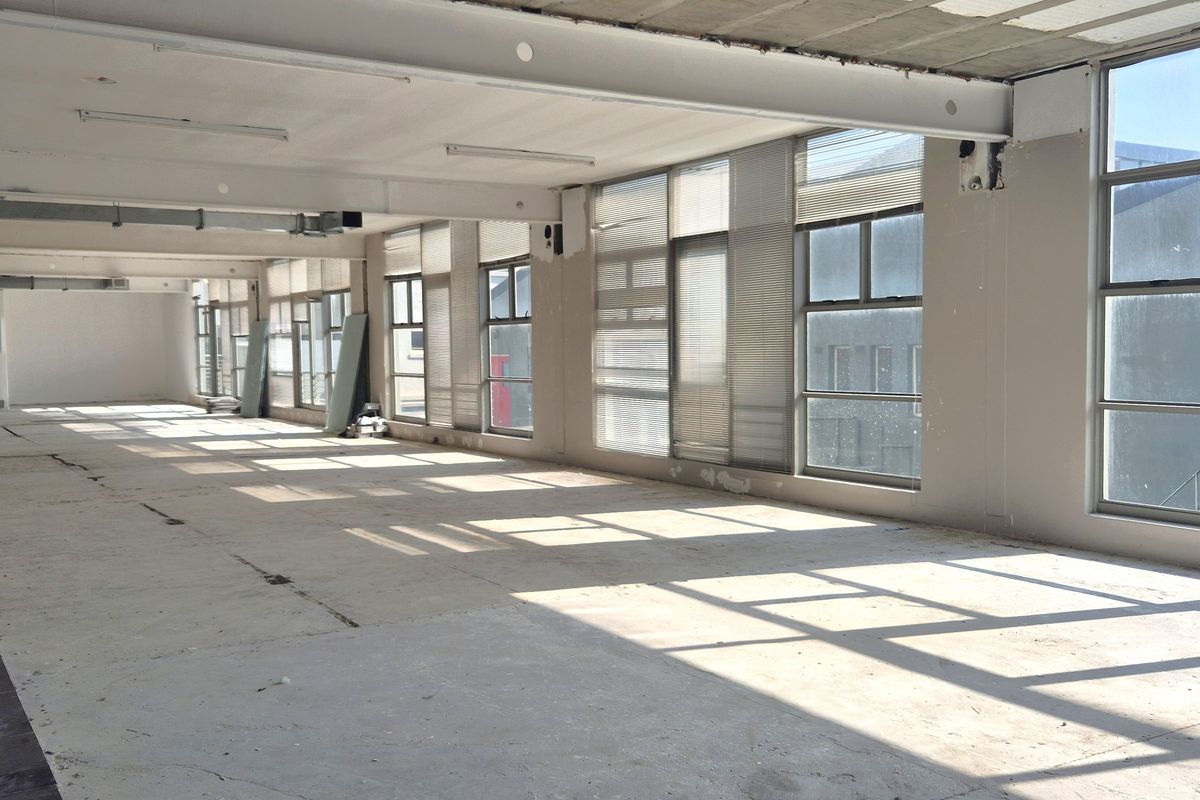 Spacious open-plan office area featuring large windows, exposed industrial-style ceiling ducting, and unfinished concrete flooring, offering a blank canvas for custom fit-out.