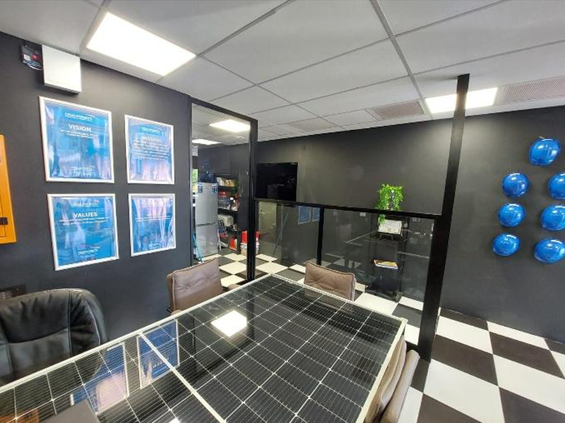Modern office meeting space featuring a glass partition, checkered flooring, and recessed ceiling lighting.