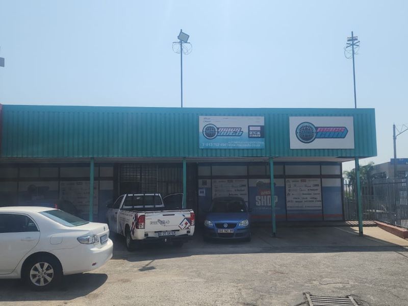 Front elevation of an industrial commercial property featuring a corrugated metal facade, external lighting, and a paved forecourt area.
