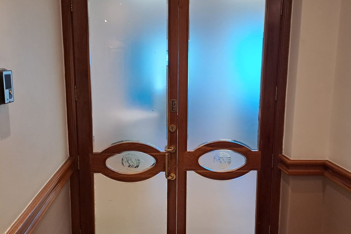 A set of double wooden doors with frosted glass panels and decorative oval inserts, featuring a secure electronic access control system.