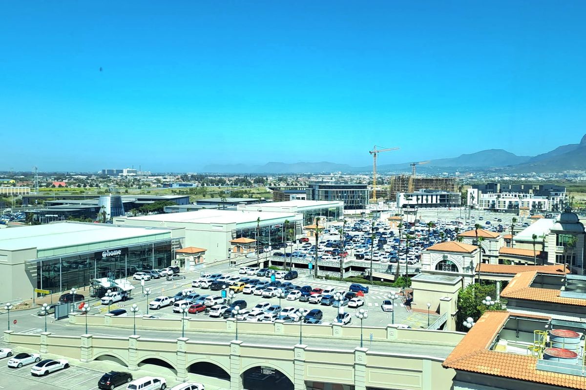 Elevated aerial view overlooking a commercial office and retail precinct with extensive parking facilities and surrounding urban landscape.