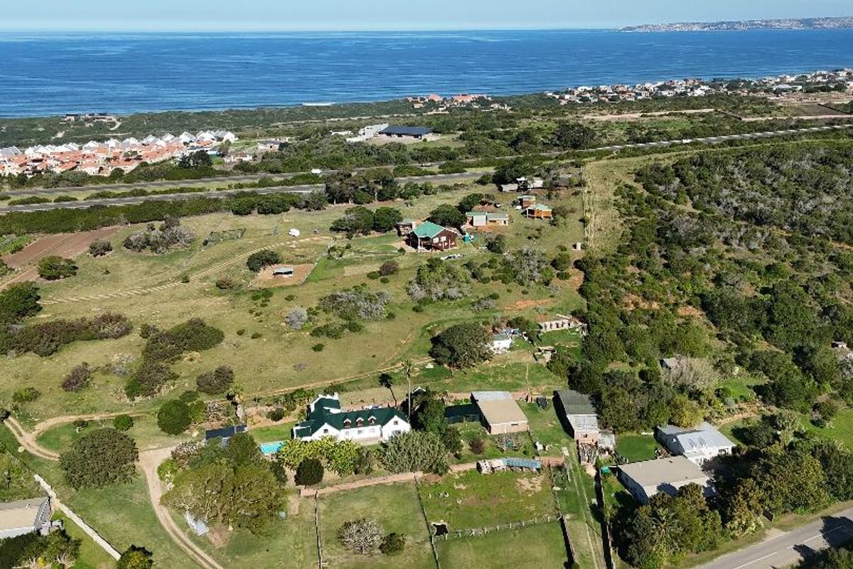 Aerial view of a coastal farm property featuring multiple outbuildings, a swimming pool, and expansive grounds with proximity to the ocean.