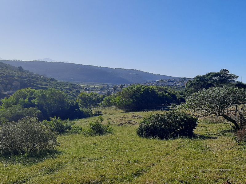 A scenic landscape view overlooking the farm property with rolling hills, natural vegetation, and perimeter wire fencing.