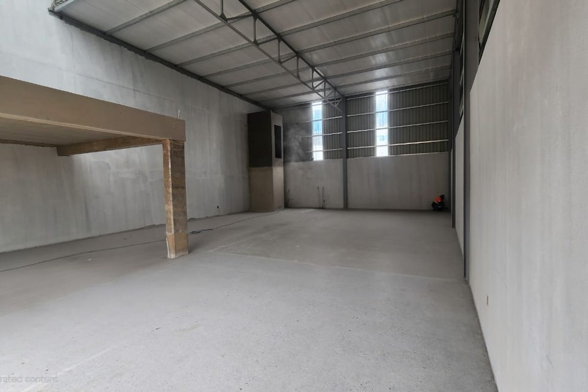 Spacious industrial warehouse unit featuring high ceilings with exposed steel trusses, concrete flooring, and a mezzanine level, offering versatile space for various business operations.