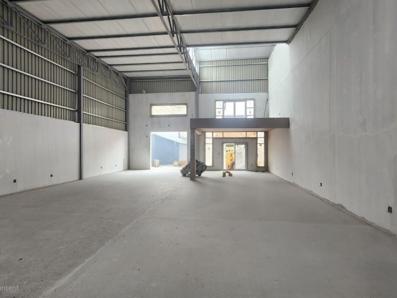 Spacious industrial warehouse unit featuring high ceilings, exposed steel trusses, concrete flooring, and a mezzanine level, offering versatile space for various commercial operations.