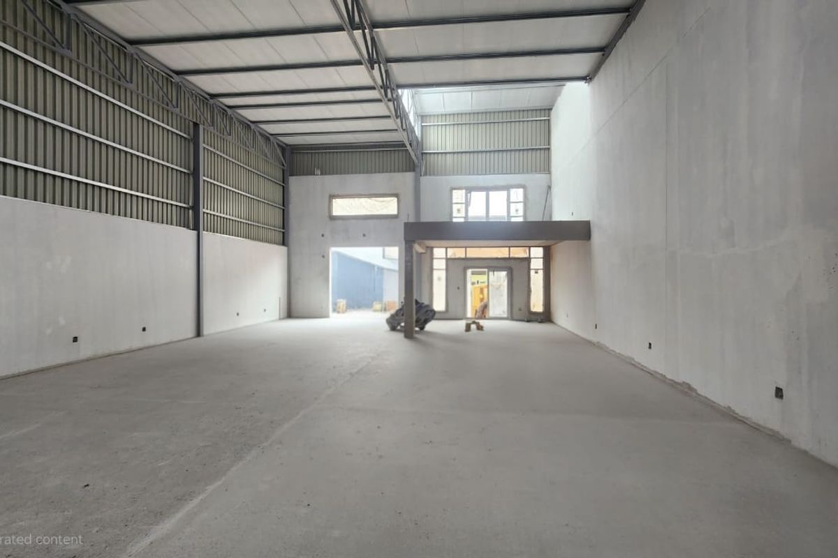 Spacious industrial warehouse unit featuring high ceilings, exposed steel trusses, concrete flooring, and a mezzanine level, offering versatile space for various commercial operations.