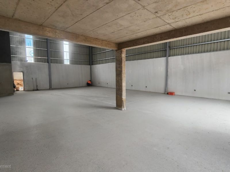 Spacious industrial utility area featuring concrete flooring, exposed ceiling, and steel structural support, suitable for warehouse or workshop use.