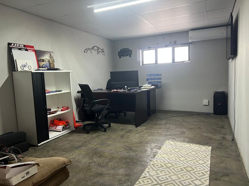 Functional office space featuring concrete flooring, air conditioning, and a horizontal window, suitable for a professional workspace.