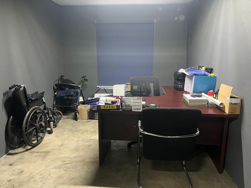 A functional office space featuring concrete flooring and a roller blind, currently used as a workspace.