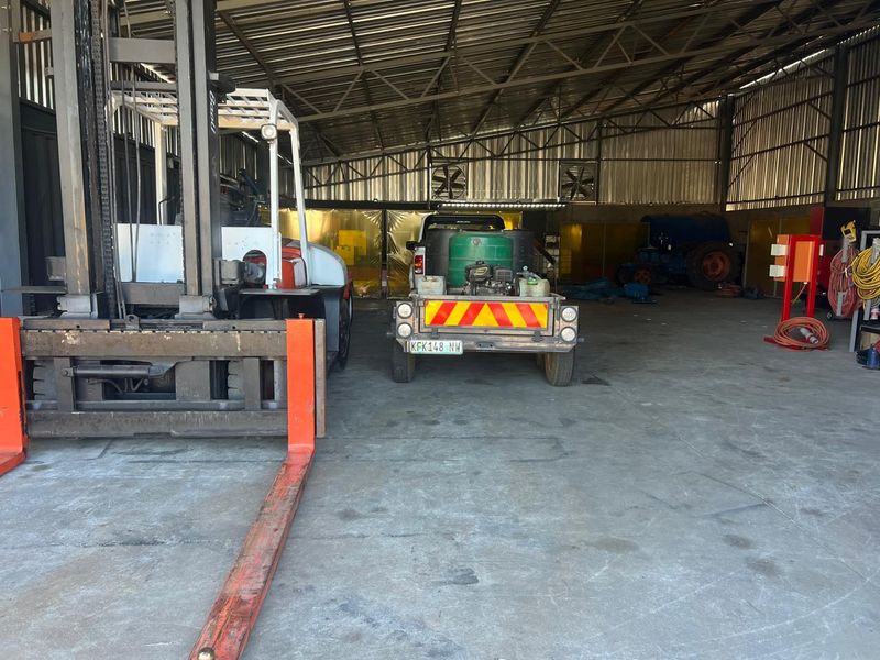 Spacious industrial garage or workshop area featuring high ceilings, concrete flooring, and metal structural framing, suitable for heavy equipment storage or operational use.