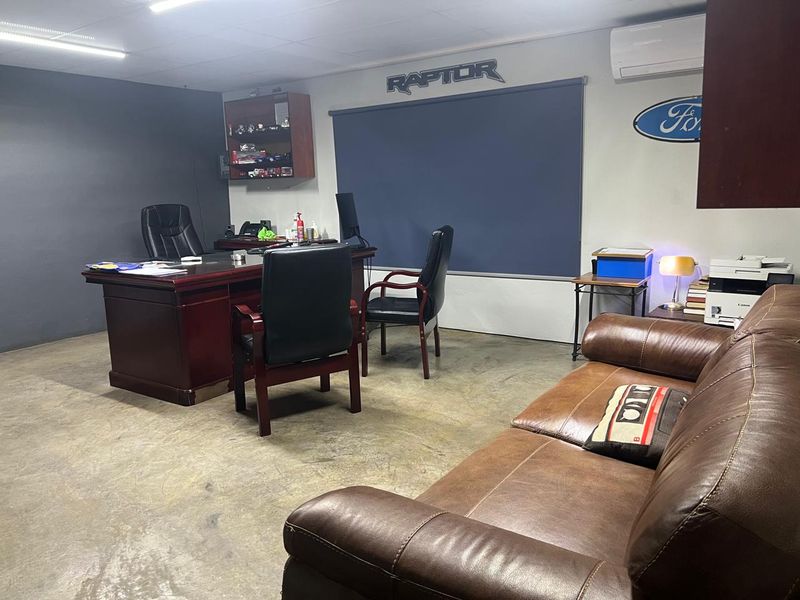 A functional office space featuring concrete flooring, built-in shelving, and an integrated air conditioning unit, suitable for a professional business environment.