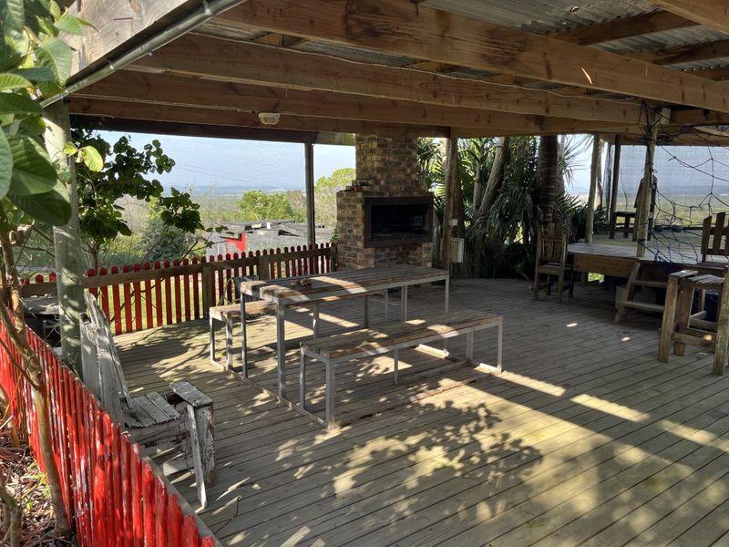 Covered outdoor patio featuring timber decking, a built-in brick braai, and scenic views, providing a rustic space for outdoor entertainment.