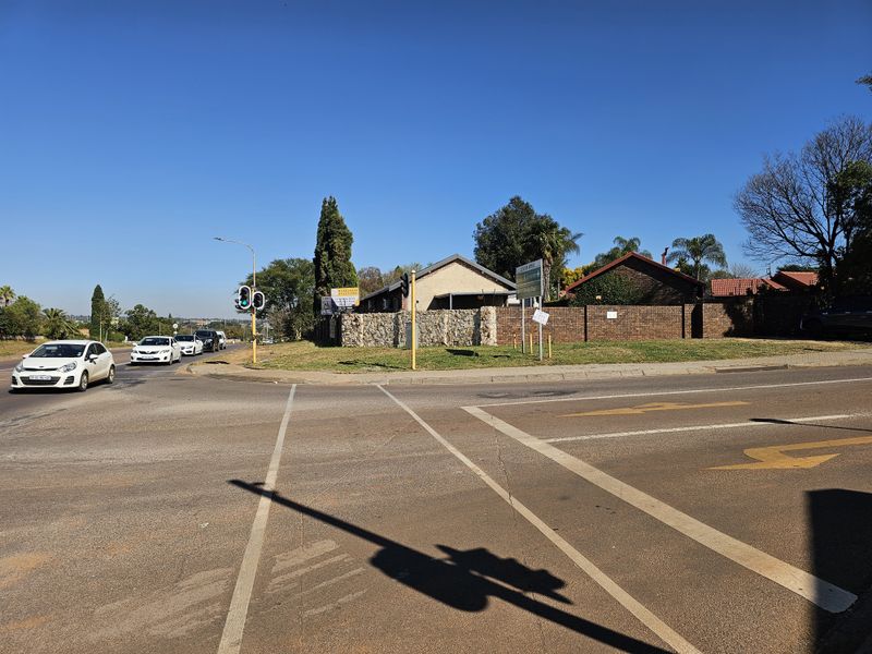 Street level view of the property corner featuring stone and brick boundary walls at a busy intersection.