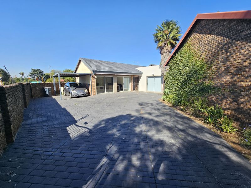 Front exterior view of the office property featuring a spacious paved driveway, a covered carport, and brick wall finishes.