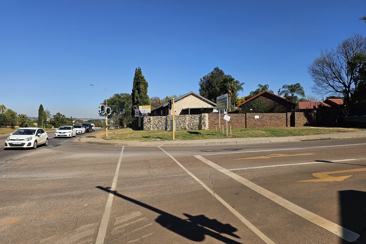 Street level view of the property corner featuring stone and brick boundary walls at a busy intersection.