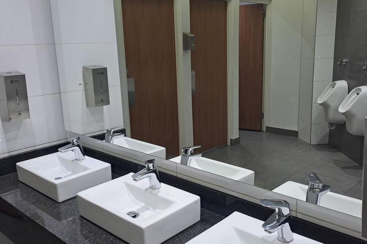 Modern office restroom featuring a triple vanity with granite countertop, vessel sinks, chrome fixtures, and wall-mounted urinals in a tiled finish.