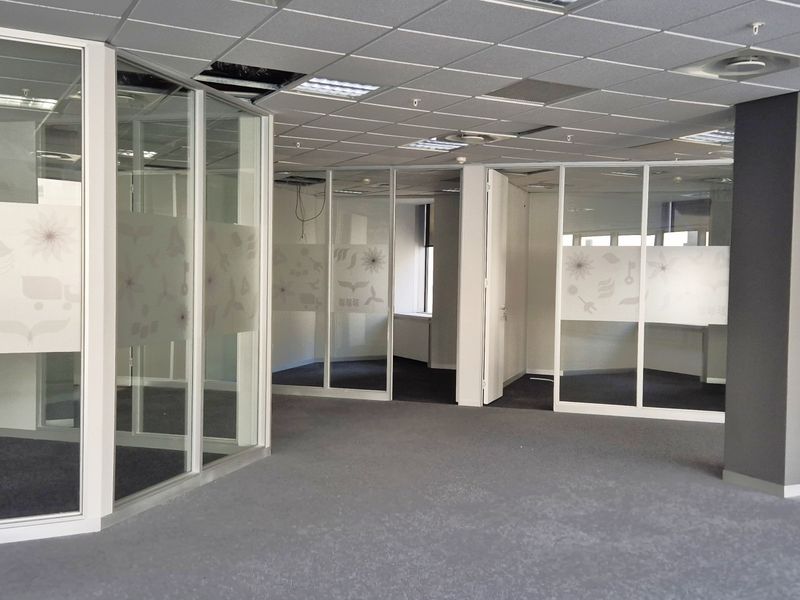 Open plan office space featuring glass partitioned offices, suspended ceilings, and carpeted flooring, currently vacant and requiring minor ceiling repairs.
